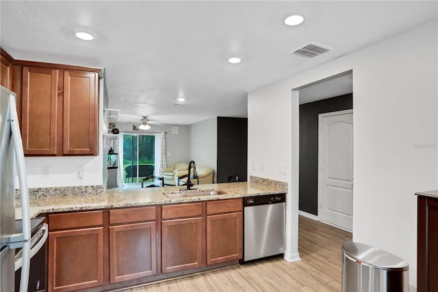 kitchen featuring visible vents, dishwasher, light wood-style flooring, stove, and a sink