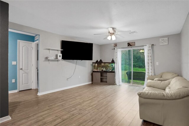 living area featuring light wood-style floors, baseboards, and a ceiling fan