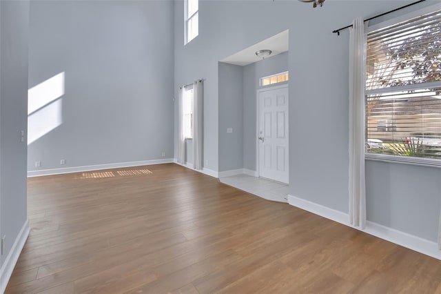 interior space featuring a towering ceiling, baseboards, and wood finished floors