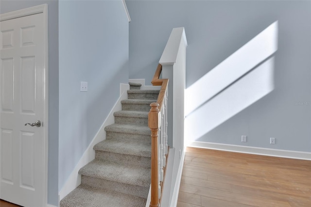 staircase featuring baseboards and wood finished floors