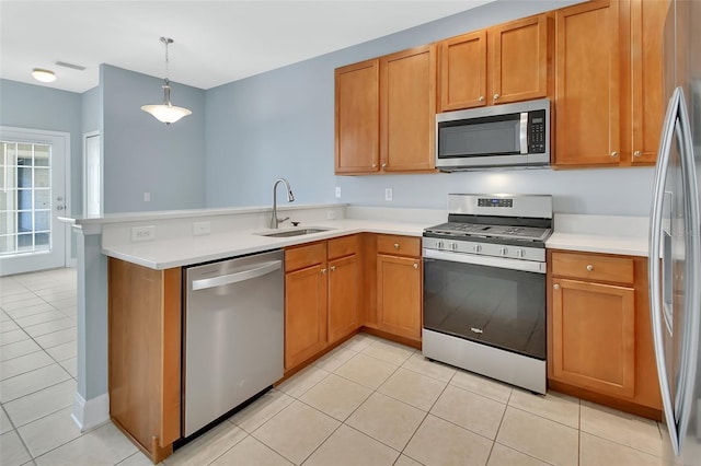 kitchen featuring light tile patterned floors, light countertops, appliances with stainless steel finishes, a sink, and a peninsula