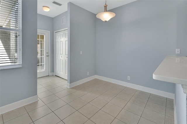 unfurnished dining area featuring light tile patterned flooring, visible vents, and baseboards