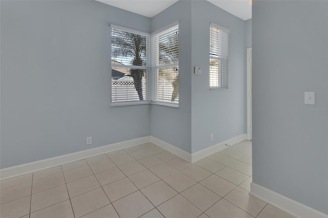 spare room with baseboards and light tile patterned floors