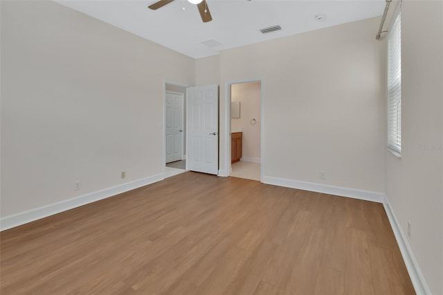 unfurnished room with light wood-style floors, visible vents, baseboards, and a ceiling fan