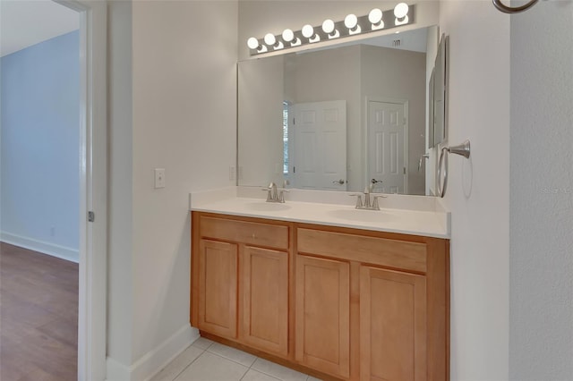 bathroom featuring double vanity, tile patterned flooring, baseboards, and a sink