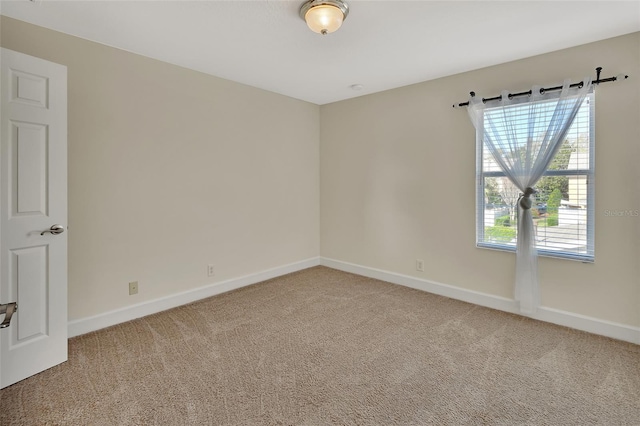 carpeted empty room featuring baseboards