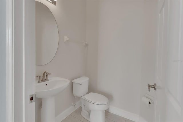 half bathroom with a sink, tile patterned flooring, toilet, and baseboards