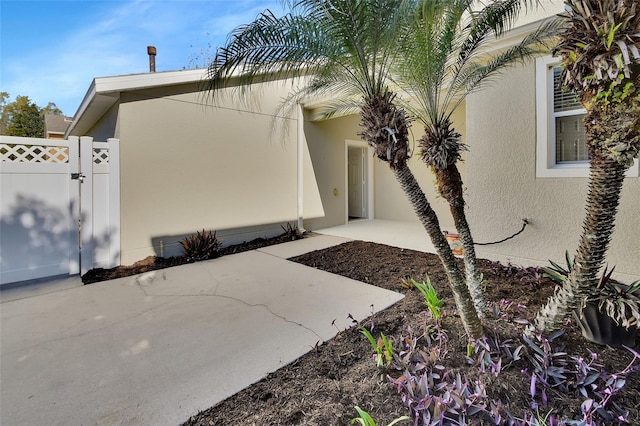 doorway to property with a patio, fence, a gate, and stucco siding