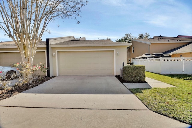 view of front of property with concrete driveway, an attached garage, fence, and stucco siding