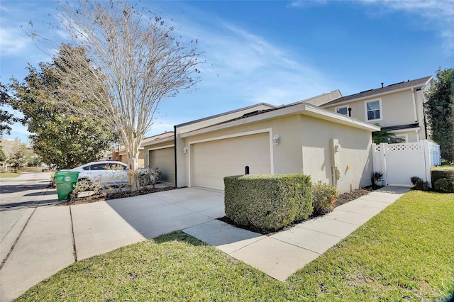 view of side of home with a garage, driveway, a lawn, fence, and stucco siding