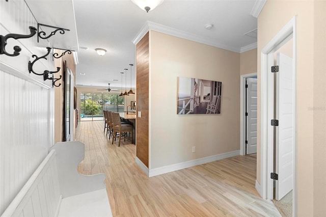 corridor featuring light wood finished floors, baseboards, and ornamental molding