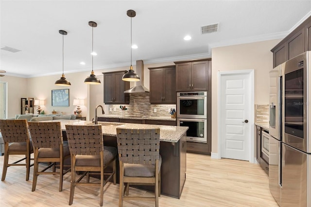 kitchen with dark brown cabinetry, visible vents, appliances with stainless steel finishes, open floor plan, and a sink