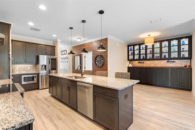 kitchen featuring light wood-style flooring, stainless steel appliances, a sink, visible vents, and tasteful backsplash