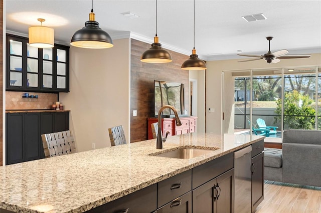 kitchen featuring visible vents, dishwasher, hanging light fixtures, light wood-style floors, and a sink