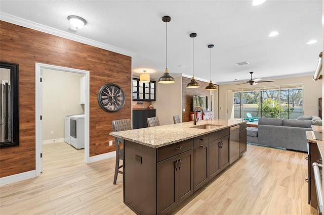 kitchen with dishwasher, wooden walls, and a sink