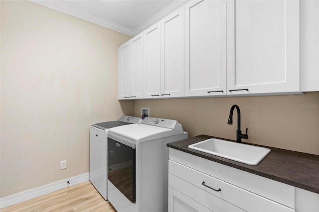 washroom with separate washer and dryer, a sink, ornamental molding, light wood-type flooring, and cabinet space