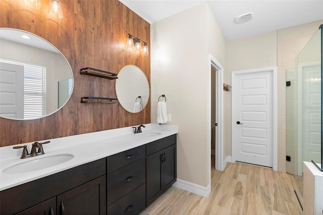 full bathroom featuring double vanity, wood finished floors, a stall shower, and a sink