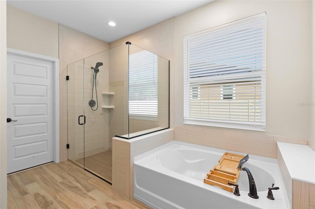 bathroom with a garden tub, wood finished floors, and a stall shower