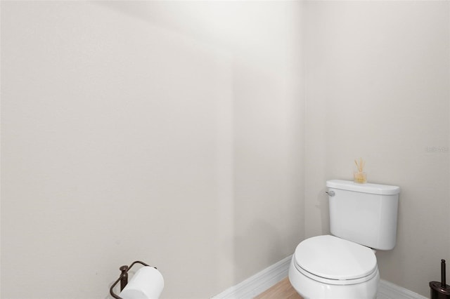 bathroom with toilet, baseboards, and wood finished floors