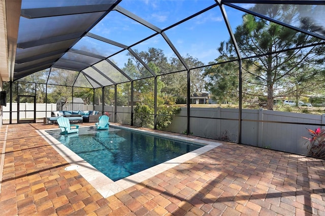 view of pool featuring glass enclosure, a fenced backyard, an outdoor hangout area, and a patio