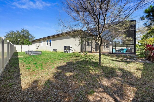 view of yard featuring glass enclosure and a fenced backyard