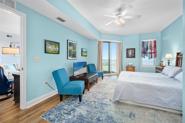 bedroom with a ceiling fan, visible vents, baseboards, and wood finished floors