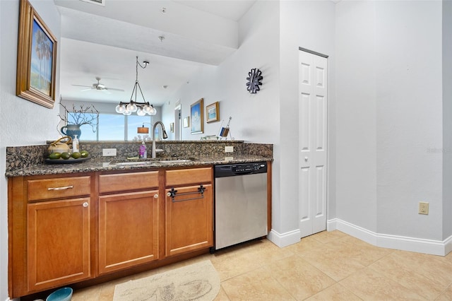 kitchen featuring stainless steel dishwasher, dark stone countertops, a sink, and brown cabinets