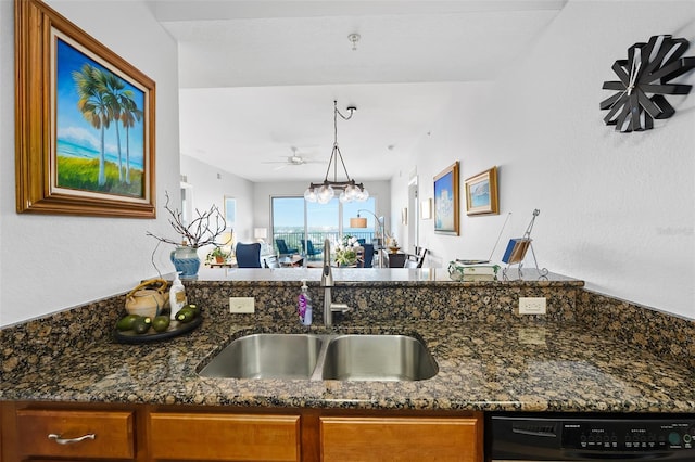 kitchen with dishwasher, brown cabinetry, dark stone countertops, and a sink