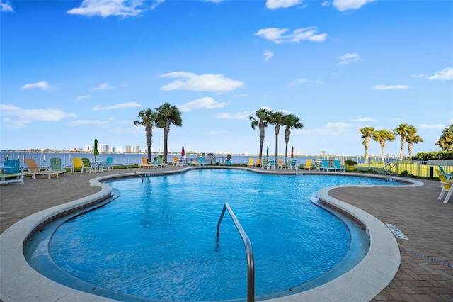 community pool featuring a patio area, fence, and a city view