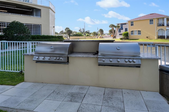 view of patio with an outdoor kitchen, a grill, and fence