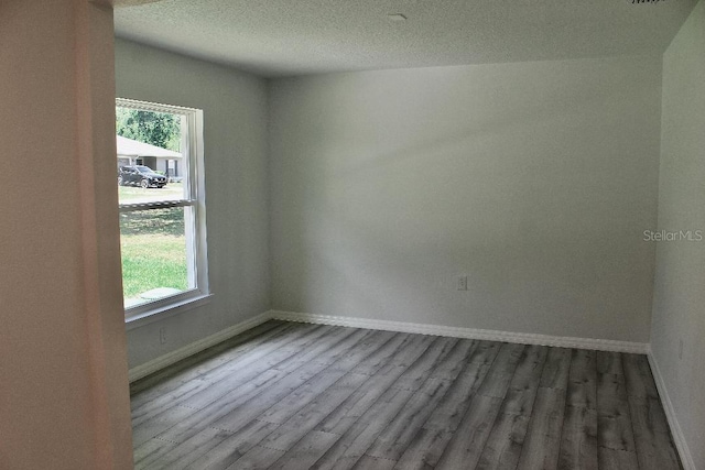 spare room with wood finished floors, baseboards, and a textured ceiling