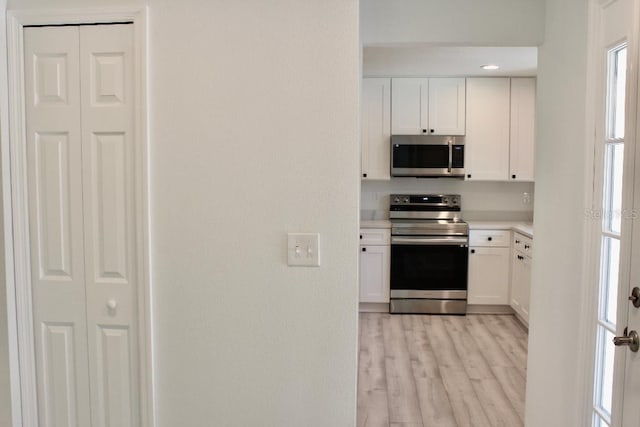 kitchen featuring light countertops, white cabinets, light wood-style floors, and stainless steel appliances