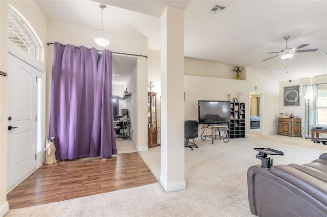 carpeted living room featuring visible vents, vaulted ceiling, a ceiling fan, and wood finished floors