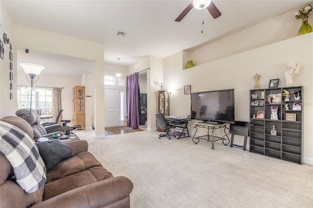 carpeted living room with baseboards, visible vents, and a ceiling fan