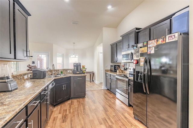 kitchen featuring light wood-style flooring, a peninsula, a sink, visible vents, and appliances with stainless steel finishes