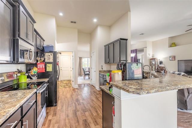 kitchen with a peninsula, visible vents, a kitchen breakfast bar, appliances with stainless steel finishes, and light wood-type flooring