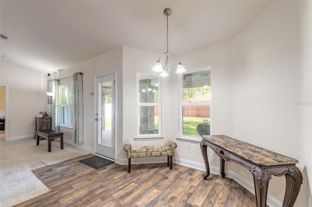 foyer entrance featuring a notable chandelier, visible vents, vaulted ceiling, wood finished floors, and baseboards