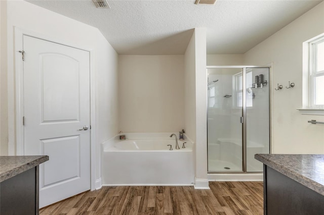 full bath with wood finished floors, a textured ceiling, vanity, a shower stall, and a bath