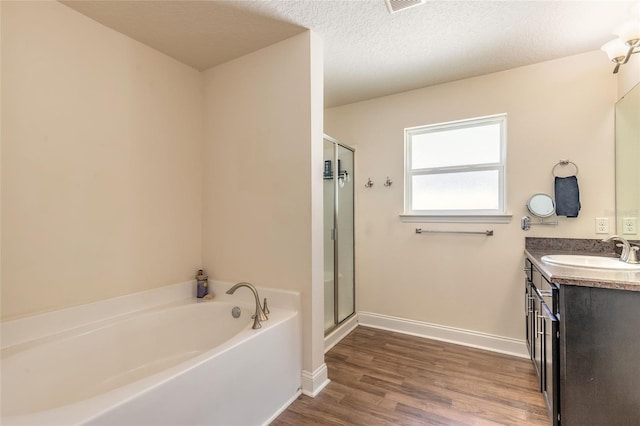 bathroom featuring a garden tub, a stall shower, wood finished floors, and a textured ceiling