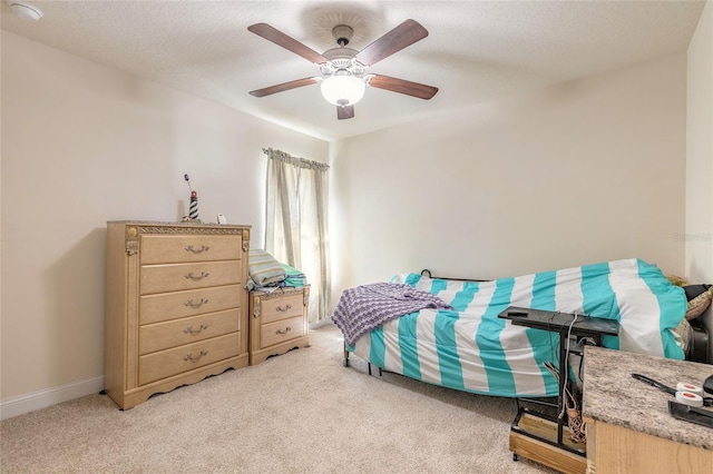 bedroom with light carpet, a textured ceiling, baseboards, and a ceiling fan