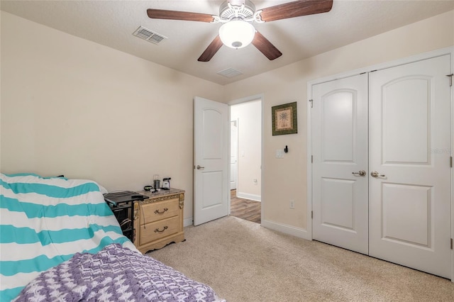 bedroom with ceiling fan, light carpet, visible vents, baseboards, and a closet