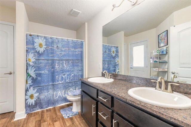 full bathroom featuring double vanity, a sink, toilet, and wood finished floors