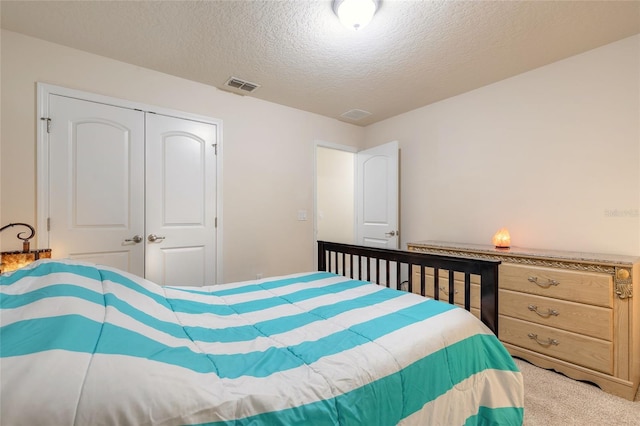 bedroom featuring carpet floors, a textured ceiling, visible vents, and a closet