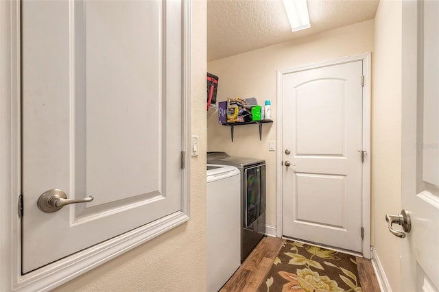 laundry room featuring a textured ceiling, laundry area, wood finished floors, baseboards, and washer and clothes dryer