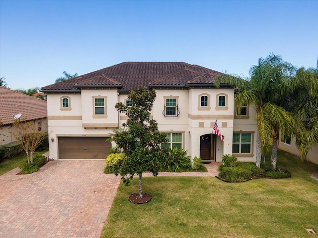 mediterranean / spanish home with an attached garage, a front yard, decorative driveway, and stucco siding