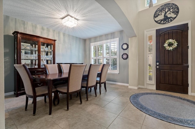 dining room with light tile patterned floors, arched walkways, and baseboards