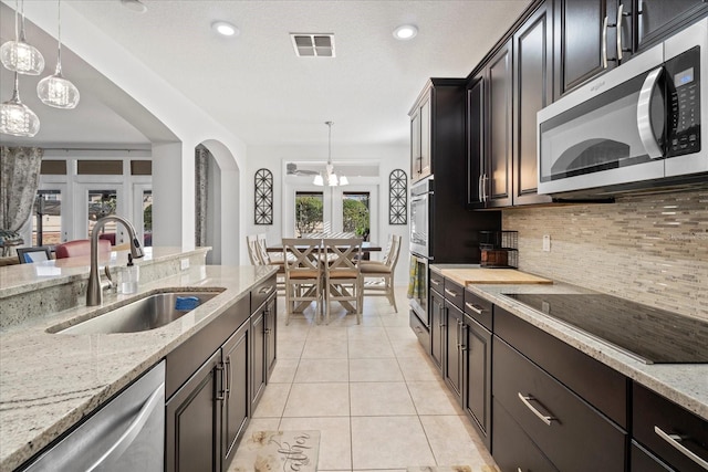 kitchen featuring stainless steel appliances, visible vents, backsplash, light tile patterned flooring, and a sink