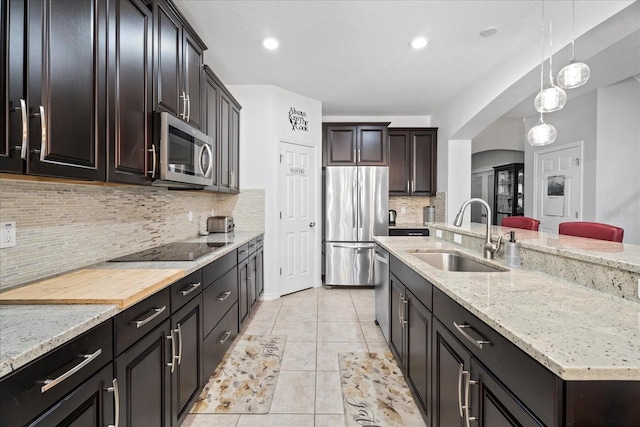 kitchen with light tile patterned floors, decorative backsplash, hanging light fixtures, stainless steel appliances, and a sink