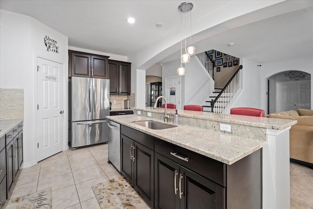 kitchen with arched walkways, stainless steel appliances, tasteful backsplash, open floor plan, and a sink