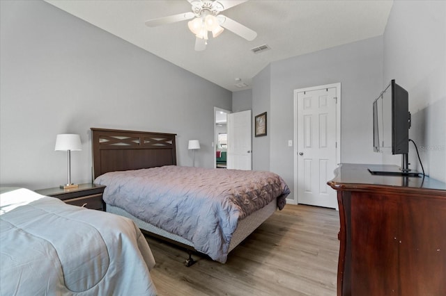 bedroom featuring lofted ceiling, light wood-style flooring, visible vents, and a ceiling fan